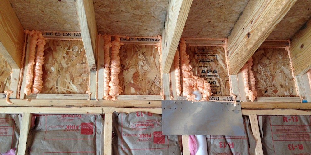 Sealed floor joist bays above a building enclosure wall
